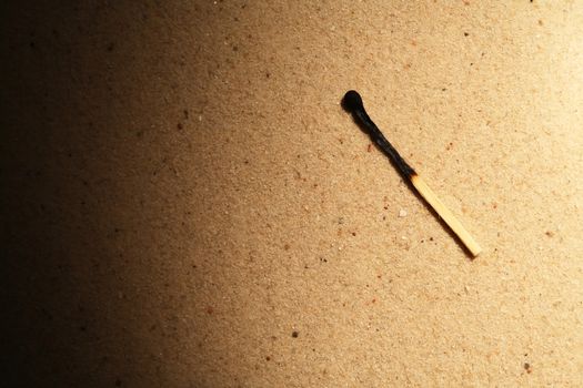 One burnt match on sand background with beam of light