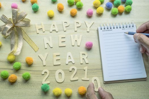 notepad with pencil, gift  and number 2021 on wood backgorund for happy new year 2021 image.For welcome new year photo.