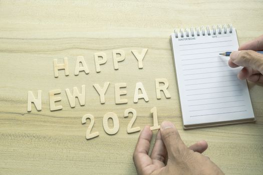 notepad with pencil, gift  and number 2021 on wood backgorund for happy new year 2021 image.For welcome new year photo.