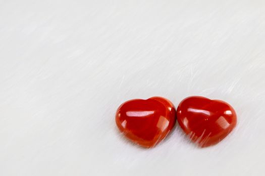 Two red wooden hearts symbol of love on white fur background, Saint Valentine Day celebration