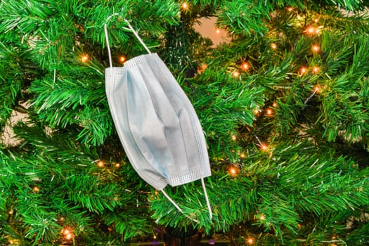 Coronavirus face protection plain design used as seasonal ornament at the branches of an artificial tree.