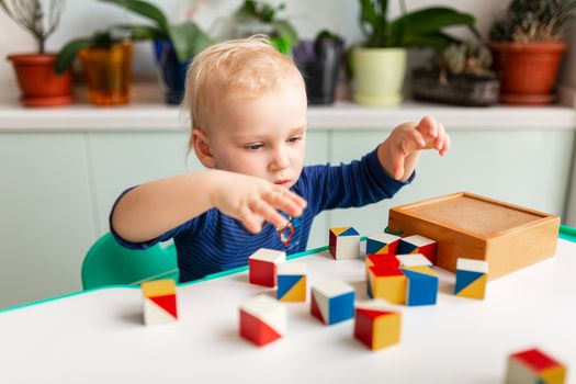 Baby playing with wooden blocks creating a pattern. Nikitin unicube game