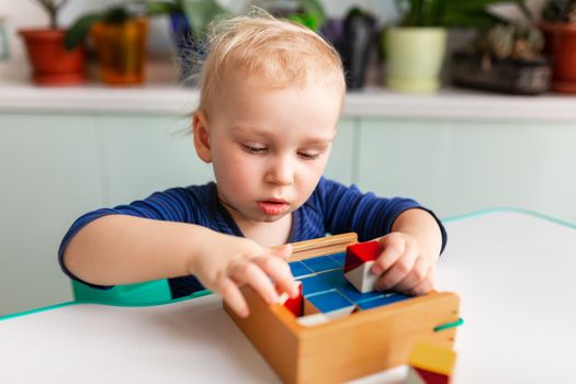 Baby playing with wooden blocks creating a pattern. Nikitin unicube game