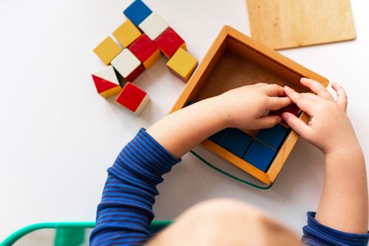 Baby playing with wooden blocks creating a pattern, focusing on hands. Nikitin unicube game