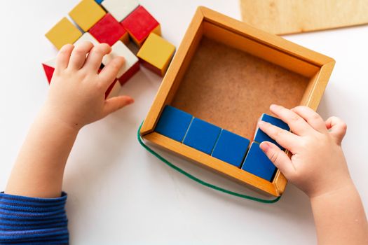 Baby playing with wooden blocks creating a pattern, focusing on hands. Nikitin unicube game