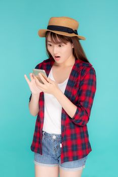 Beautiful young asian woman touch smart mobile phone with surprise in vacation isolated blue background, girl talking chat message excited on smartphone in travel summer trip, communication concept.