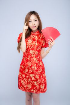 Beautiful portrait young asian woman cheongsam dress smiling and think idea holding red envelope on white background, girl wear qipao celebrate with exciting, happy Chinese New Year, holiday concept.