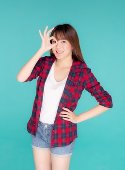 Beautiful happy young asian woman wear travel summer gesture ok sign with hand on eye having vision isolated on blue background, asia teenager girl expression with cheerful and fun while trip.