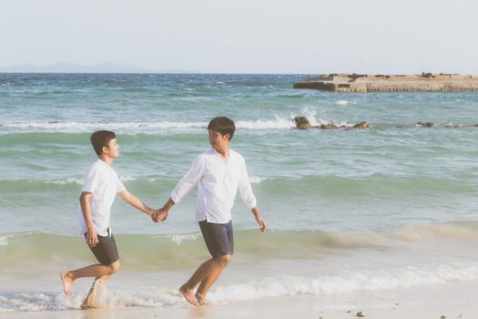 Homosexual portrait young asian couple running with cheerful together on beach in summer, asia gay going tourism for leisure and relax with happiness in vacation at sea, LGBT legal concept.