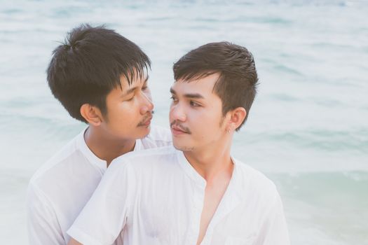 Homosexual portrait young asian couple standing hug and look together on beach in summer, asia gay going tourism for leisure and relax with romantic and happy in vacation at sea, LGBT legal concept.