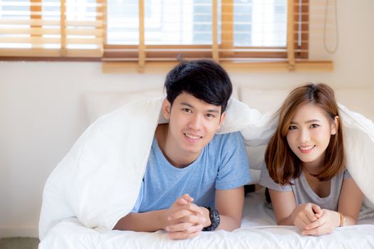 Beautiful portrait young asian couple relax and satisfied together in bedroom at home, family lying on bed confident with cheerful and happy with relationship, man and woman dating.
