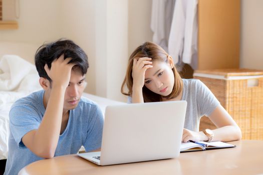 Young asian couple stressed and worried about finance of problem business together, man and woman looking laptop and frustrated, family unhappy and depression about debt, lifestyle concept.
