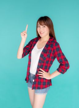 Beautiful portrait young asian woman smiling gesture pointing something and excited summer holiday isolated blue background, asia girl confident and cheerful with journey, travel concept.