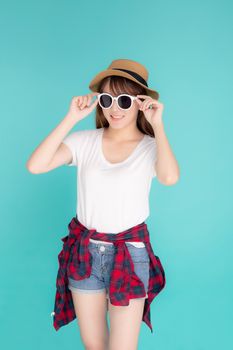 Beautiful portrait young asian woman wear hat and holding sunglasses smiling confident enjoy journey summer trip in vacation isolated on blue background, tourist asia girl cheerful with travel.