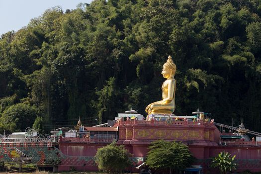 Chiang Rai Thailand 12.10.2015 large seated, crossed leg golden Buddha by river northern Thailand. High quality photo