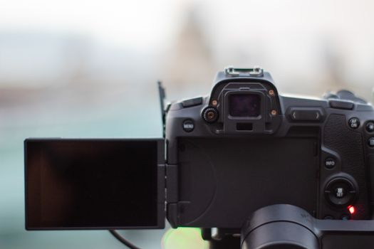 Camera with black screen overlooking the blurry Millennium Bridge and Saint Paul Cathedral. Camera capturing a cityscape from London. Photography and video equipment