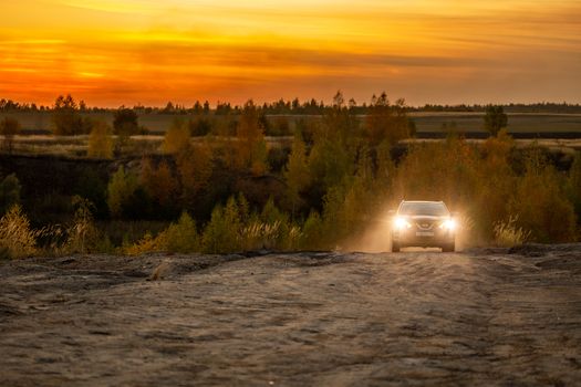 VOLKOVO, RUSSIA - OCTOBER 4, 2020: Blue Nissan Qashqai climbing up on dry dusty dirt road at autumn golden sunset offroad.