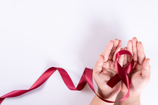 Aids awareness, woman hands holding red ribbon on white background with copy space for text. World Aids Day, Healthcare and medical concept.