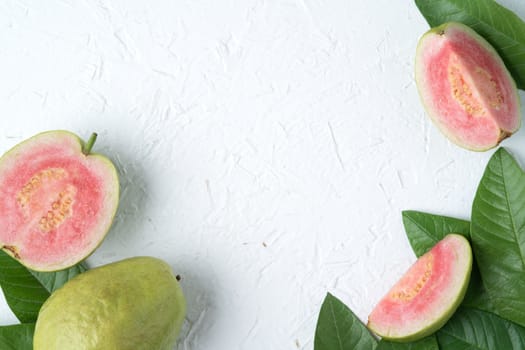 Top view, flat lay of delicious beautiful Red guava with fresh green leaves isolated on white table background, studio overhead table shot with copy space.