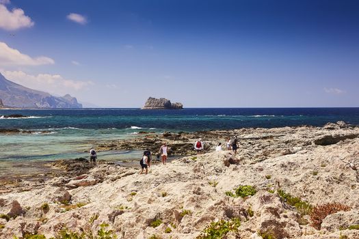 GRAMVOUSA - BALOS, THE CRETE ISLAND, GREECE - JUNE 4, 2019: The people on the beach of Gramvousa island. The Gramvousa island is famous for its pirate castle on the top of the mountain.