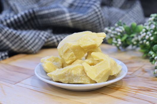 Natural cocoa butter oil in a wooden bowl on a brown background.