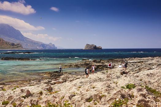 GRAMVOUSA - BALOS, THE CRETE ISLAND, GREECE - JUNE 4, 2019: The people on the beach of Gramvousa island. The Gramvousa island is famous for its pirate castle on the top of the mountain.