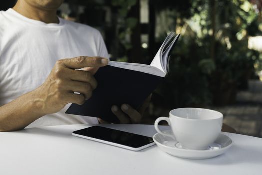 A man reading a book with coffee cup. Man sitting in chair at home, reading book and relaxing.