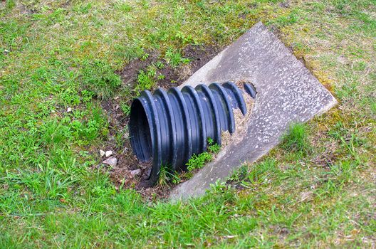 Industrial wastewater. Sewer drains from a plastic corrugated black sewer pipe into a sewer manhole in the city