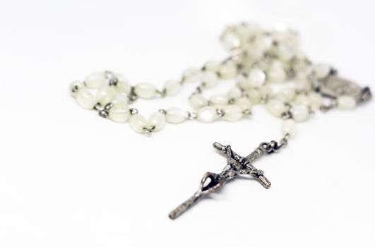 White pearl rosary with silver crucifix isolated on a white background. Prayer and devotion. Religious object.