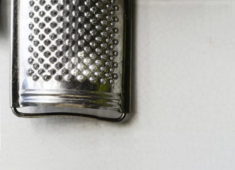 Old steel grater hanging on a tiled wall. Cooking utensils. Cheese grater