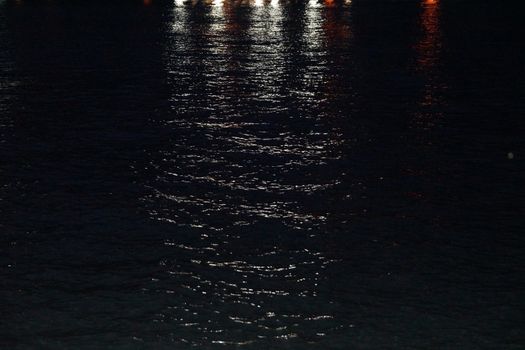 coastal city lights are reflected in sea water.