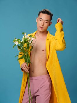 A handsome man with a bouquet of white flowers and in pink trousers is gesturing with his hands. High quality photo