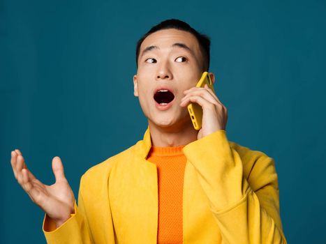 business man talking on the phone on blue background cropped view of yellow jacket. High quality photo