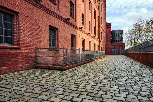 paved street and renovated buildings of an old brewery in the city of Poznan