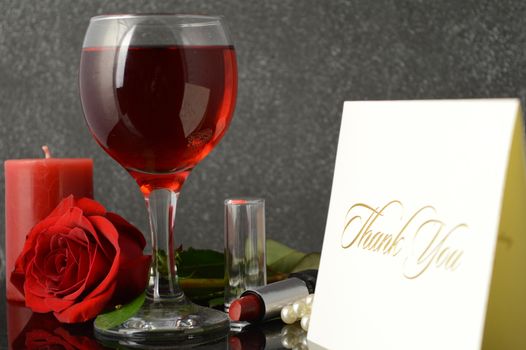 A warm thank you card next to a glass of red wine.