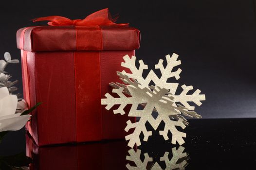 A closeup image of a red Christmas gift with decorative items to compliament the festive season.