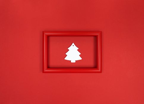 Red frame, with white wooden Christmas tree toy inside.