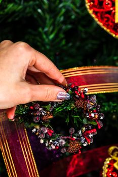 Decorating Christmas tree, hand putting Christmas decorations on fir branches. Christmas hanging decorations.