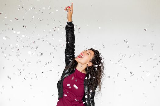 The emotion of success. Happy sexy brunette girl is enjoying celebrating with confetti on a white background.