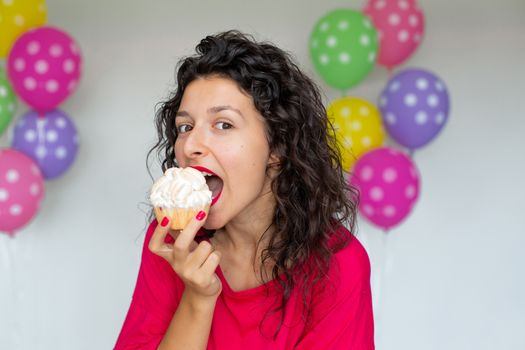 Happy Birthday. Sexy brunette girl posing with balloons, fireworks, colorful balloons and holiday cake on a white background.