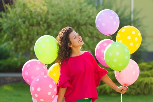 Young bright joyful brunette girl with colorful balloons. Happy lifestyle.