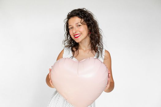 Sexy brunette girl posing with heart-shaped balloons on a white background.