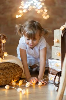 .Cute little girl sitting on the floor among the new year garlands.