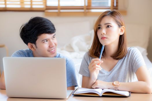 Beautiful young asian couple calculate expenses finance with laptop and planning together, woman writing notebook or note budget household, lifestyle family and business concept.