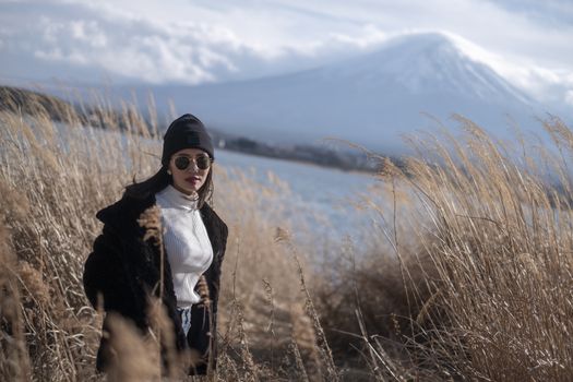 Beautiful smiling woman tourists are traveling and feel happy with Mt Fuji in the morning on the lake kawaguchiko, Japan