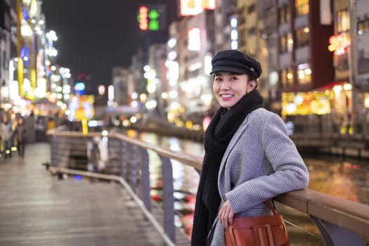 Beautiful smiling woman tourists traveling in walking at street shopping center Dotonbori in Osaka, Japan.