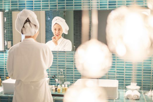 Young woman putting on makeup after shower 