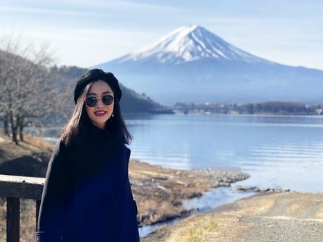 Beautiful smiling woman tourists are traveling and feel happy with Mt Fuji in the morning on the lake kawaguchiko, Japan