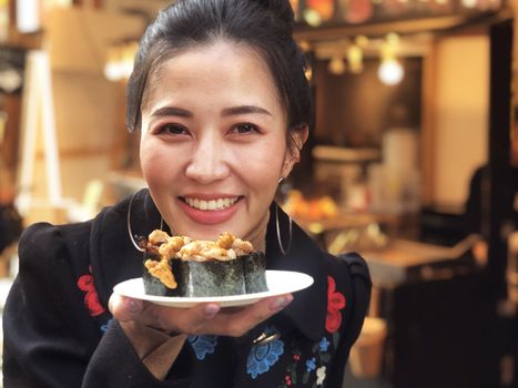 Tourist woman showing beef sushi most popular delicious food in street food tsukiji fish market,  Japan