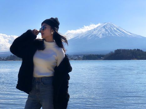 Beautiful smiling woman tourists are traveling and feel happy with Mt Fuji in the morning on the lake kawaguchiko, Japan